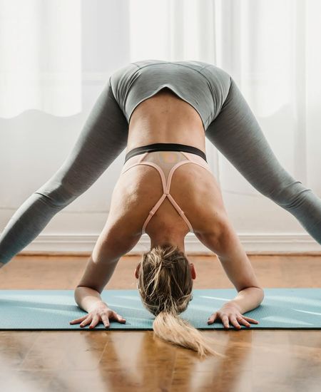 Woman in a calm yoga pose in a dark room with purple light.
